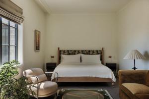 a bedroom with a white bed and a chair at The Nickel Hotel in Charleston