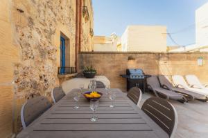 a table and chairs on a patio with a grill at Authentic Xagħra Farmhouse with Private Pool in Xagħra