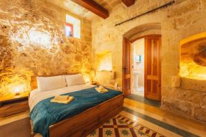 a bedroom with a bed and a stone wall at Authentic Xagħra Farmhouse with Private Pool in Xagħra +68 photos