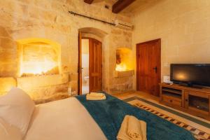 a bedroom with a bed and a tv in a room at Authentic Xagħra Farmhouse with Private Pool in Xagħra