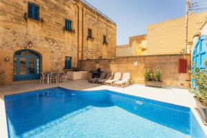 a swimming pool in front of a building at Authentic Xagħra Farmhouse with Private Pool in Xagħra