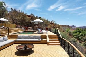 una terraza de madera con piscina, mesa y bol en The Outpost & Pel's Post en Makuleke Contract Park