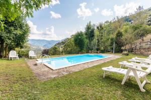 a swimming pool in a yard with two white chairs at Fidalsa Paradise Point in Cabezón de Liébana