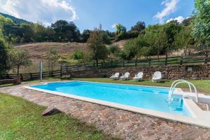 a swimming pool in a yard with chairs and a fence at Fidalsa Paradise Point in Cabezón de Liébana