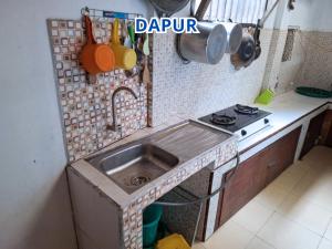 a small kitchen with a sink and a stove at Prima Homestay Tuktuk in Sinapuran