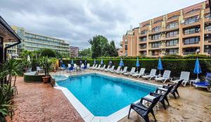 a swimming pool with chairs and umbrellas next to a building at Friends Family Hotel in Sunny Beach