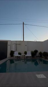 a swimming pool with two white chairs and a fence at Palm Villa in Mərdəkan