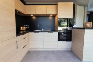 a kitchen with wooden cabinets and a sink at Delya, chalet confort, climatisation, piscine in Agde +26 photos