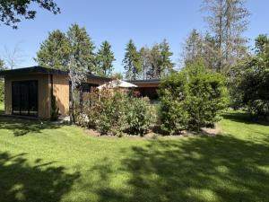 a house in a yard with green grass and trees at Wellnesslodge Kievit jacuzzi sauna and privacy in Dalerveen