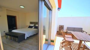 a bedroom with a bed and a balcony with a table at Apartamentos Living Sevilla Centro Maestranza in Seville