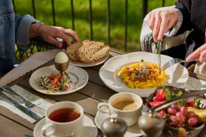 a table with plates of food and cups of coffee at Tilia Kúria - Adults only in Bózsva