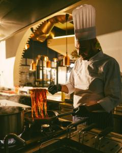 a chef cooking food in a pot in a kitchen at World Heart Hotel in Baghdād +135 photos