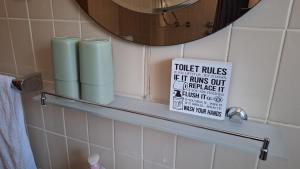 a bathroom with a toilet rules sign on a shelf at Lake Crown in Ogulin +42 photos