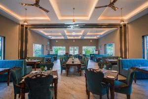 a dining room with tables and blue chairs at Mango Bloom River Resort By Excel Hotels & Resorts in Marchula