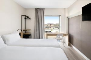 ein Schlafzimmer mit Bett, Schreibtisch und Fenster in der Unterkunft B&B HOTEL Granada in Pulianas