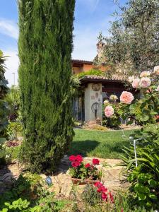 a garden with a large tree and flowers in front of a house at Il Vialetto in Cannara