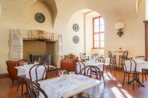 a restaurant with tables and chairs and a fireplace at QC Grand Hotel Villa Arzaga Garda Spa & Golf in Calvagese della Riviera