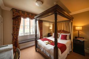 a bedroom with a canopy bed and a window at The Atherstone Red Lion Hotel in Atherstone