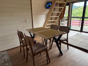 a dining room with a table and chairs and a ladder at А-фрейм У Ґазди in Synevyrsʼka Polyana