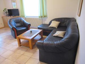 a living room with a leather couch and a coffee table at Feriendorf Mengshausen 1 in Niederaula +5 photos