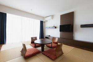a room with a table and chairs and a television at EM Wellness Kurashinohakko Lifestyle Resort in Kitanakagusuku