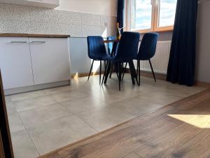 a kitchen with a table and four blue chairs at Apartament Nova Starówka 2 in Konin +22 photos
