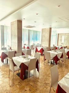 a dining room with tables and chairs with red table cloth at Hotel Playa in Bibione