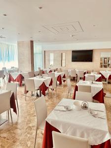 a dining room with white tables and white chairs at Hotel Playa in Bibione