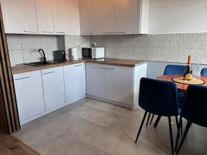 a kitchen with white cabinets and a table with a bottle of wine at Apartament Nova Starówka 2 in Konin