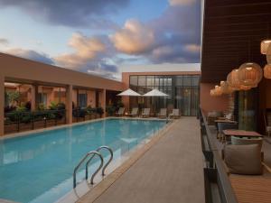 a large pool in a hotel with chairs and tables at NOVOTEL KOLWEZI in Kolwezi