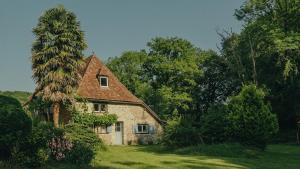 an old stone house in a field with a tree at Maison Le Grand Saule in Bugnein