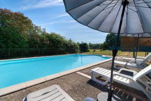 a pool with chairs and an umbrella next to it at Maison de vacances Le Tilleul in Saint-Pompont