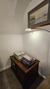a pile of books sitting on a table next to a lamp at Peake Edge Home in Chesterfield