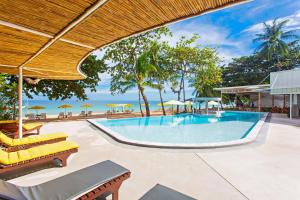 a swimming pool with chairs and umbrellas at The Fair House Beach Resort & Hotel in Chaweng Noi Beach