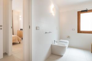 a white bathroom with a toilet and a mirror at Domus Luxi in Teulada +17 photos