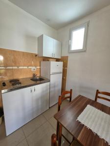a kitchen with a table and a white refrigerator at Apartmani Viki in Sutomore +15 photos