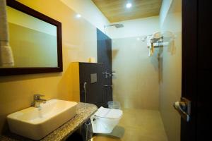 a bathroom with a sink and a toilet and a mirror at Mango Bloom River Resort By Excel Hotels & Resorts in Marchula +28 photos