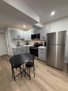 a kitchen with a table and a stainless steel refrigerator at The Onyx Suite Sleek Modern Space Private Entry in Regina