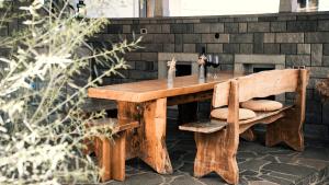 a wooden table and bench next to a brick wall at Hiša 88 in Dutovlje