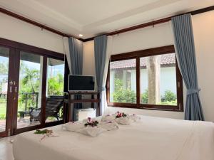 a bedroom with a bed and a tv and windows at Am Samui Resort Taling Ngam in Taling Ngam Beach