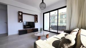 a living room with a couch and a tv and a table at Spacious & Modern - Best Larnaca Location in Larnaca