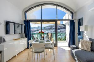 a living room with a table and a large window at Modern Sea View Apartment Near Beach & Pool Puerto Rico in Puerto Rico de Gran Canaria