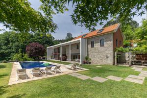 a backyard with a pool and chairs and a house at Quinta Trindade in Arouca
