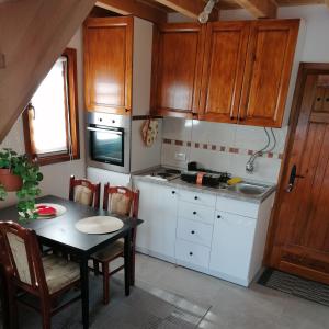 a kitchen with white cabinets and a table with chairs at Apartman Ružica in Banja