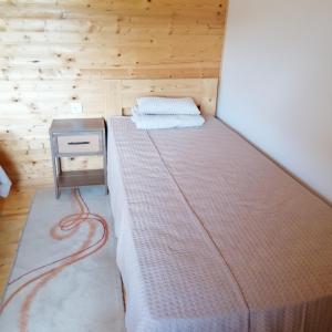 a bed in a room with a wooden wall at Apartman Ružica in Banja