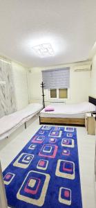 a room with two beds and a blue rug at ARZON Halal Hotel in Tashkent