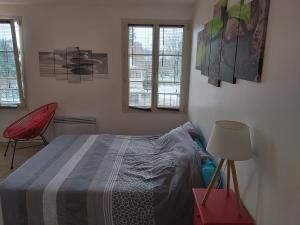 a bedroom with a bed and a red chair at Studios à la Campagne in Neuilly-lʼÉvêque