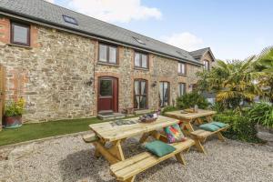 a patio with two picnic tables in front of a building at 6 Bed in Holsworthy oc-89218 in Merryfield