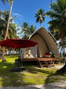 a tent with a picnic table and a red umbrella at Islas de San blas Glamping in Tubusinica +9 photos