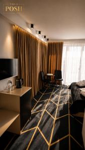 a hotel room with a bed and a desk and a television at Villa Posh All Suites Hotel & SPA in Międzywodzie